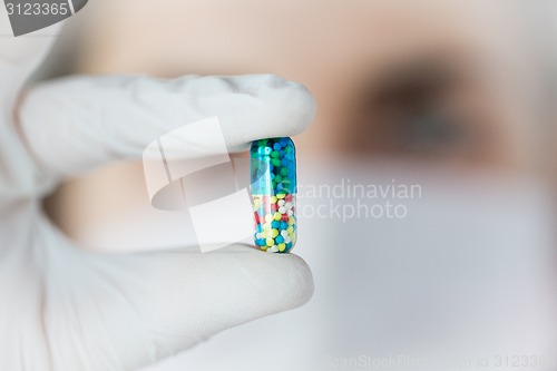 Image of close up of scientist holding pill in lab
