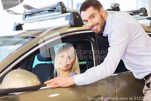 Image of happy couple buying car in auto show or salon