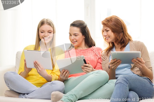 Image of three smiling teenage girls with tablet pc at home