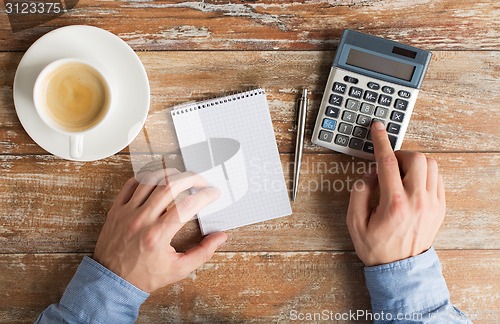 Image of close up of hands with calculator and notebook