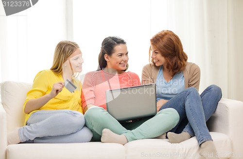 Image of smiling teenage girls with laptop and credit card