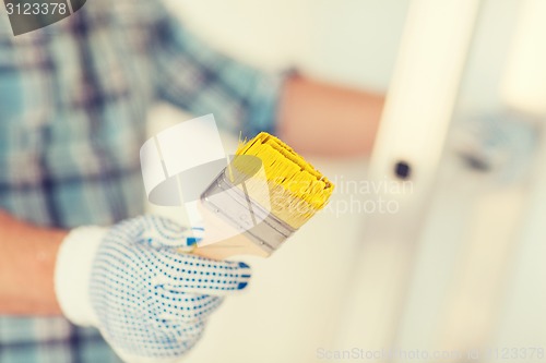 Image of close up of male in gloves holding paintbrush