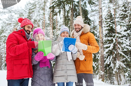 Image of smiling friends with tablet pc in winter forest