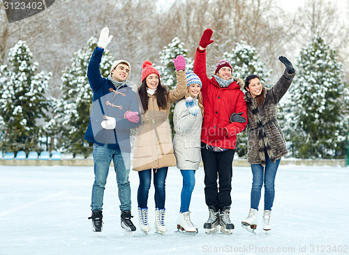 Image of happy friends ice skating on rink outdoors