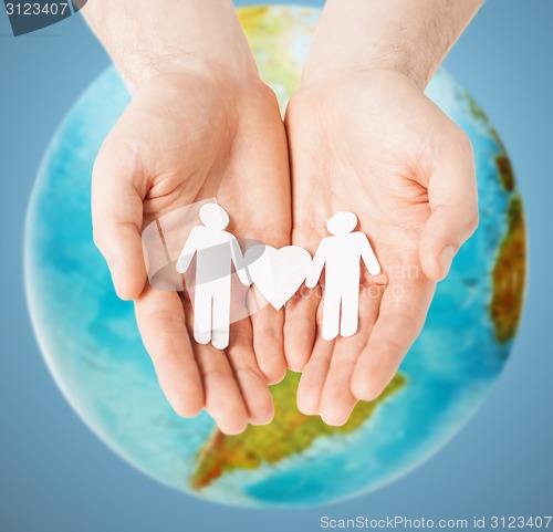 Image of male hands with paper gay couple figures and globe