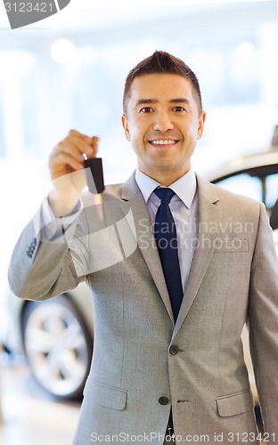 Image of happy man showing key at auto show or car salon