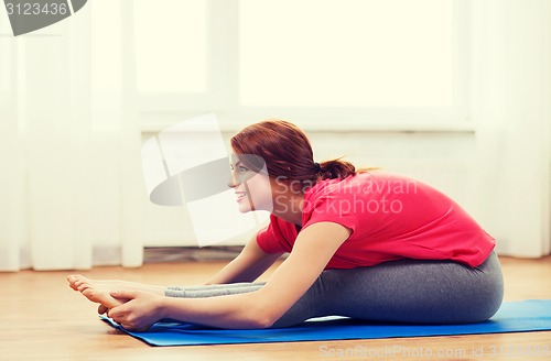 Image of smiling teenage girl streching on floor at home