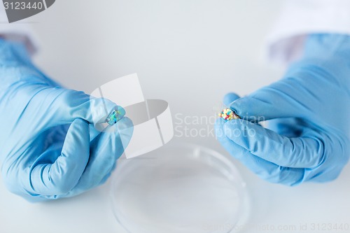 Image of close up of scientist hands holding pill in lab