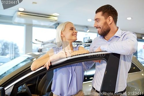 Image of happy couple buying car in auto show or salon