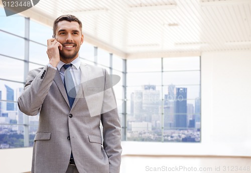 Image of happy young businessman calling on smartphone