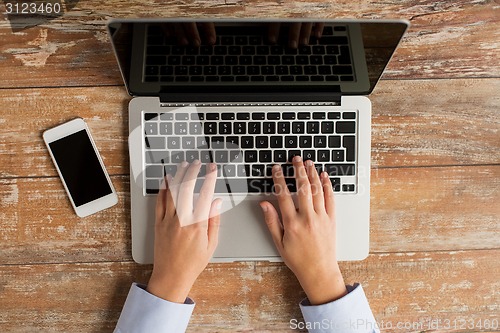 Image of close up of hands with laptop and smartphone