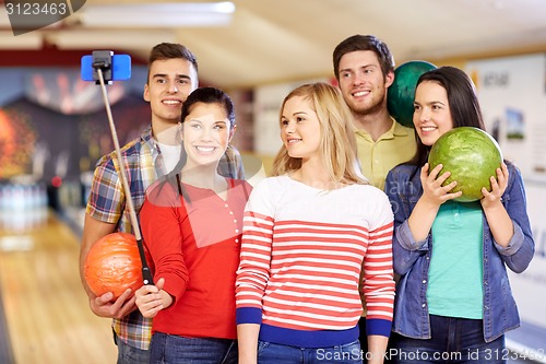 Image of happy friends taking selfie in bowling club