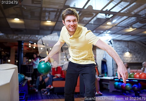 Image of happy young man throwing ball in bowling club