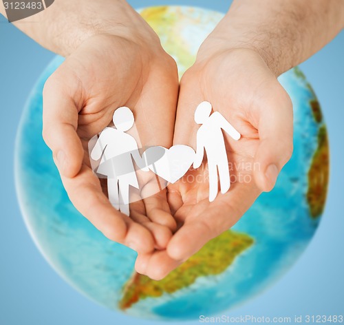 Image of human hands holding paper couple over earth globe