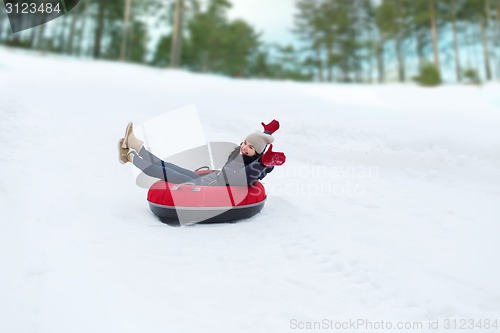 Image of happy teenage girl sliding down on snow tube