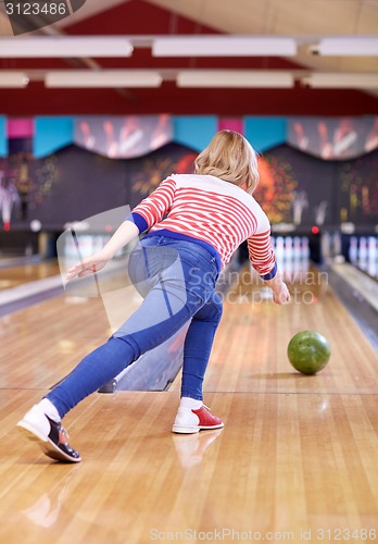 Image of happy young woman throwing ball in bowling club