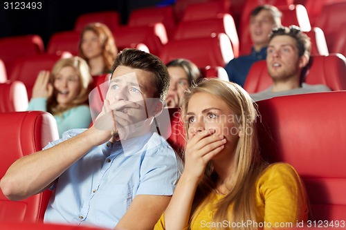 Image of happy friends watching horror movie in theater