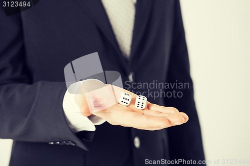 Image of mans hand holding white casino dice