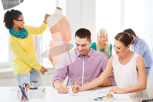 Image of smiling fashion designers working in office