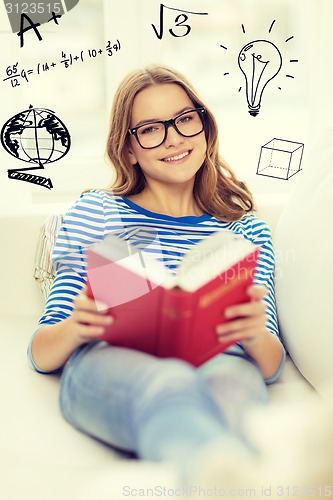 Image of smiling teenage girl reading book on couch