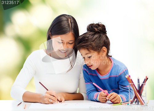 Image of happy mother and daughter drawing with pencils