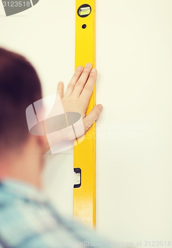 Image of close up of male with spirit level mesuring wall