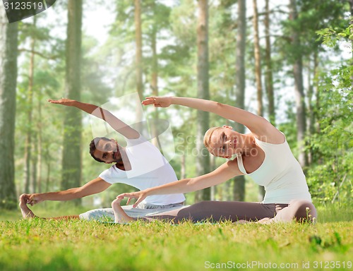 Image of happy couple stretching and doing yoga exercises