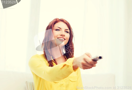 Image of smiling teenage girl with tv remote control