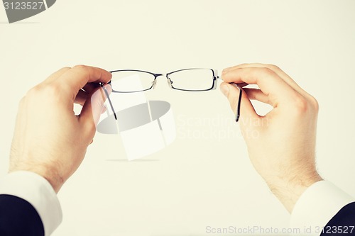 Image of man hands holding eyeglasses