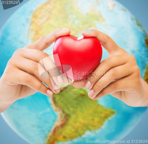 Image of woman hands holding red heart over earth globe