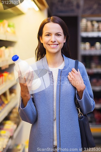 Image of happy woman holding milk bottle in market