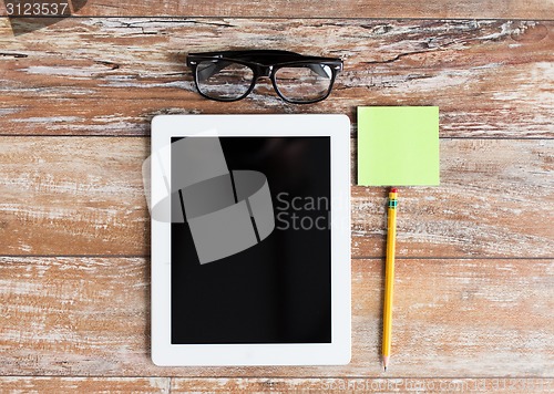 Image of close up of tablet pc, eyeglasses and pencil