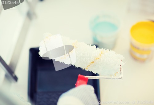 Image of close up of male in gloves holding painting roller