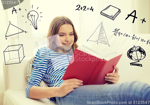 Image of smiling teenage girl reading book on couch