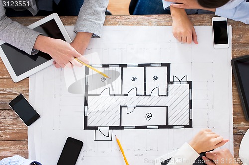 Image of business team with blueprint and gadgets