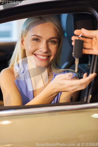 Image of happy woman getting car key in auto show or salon