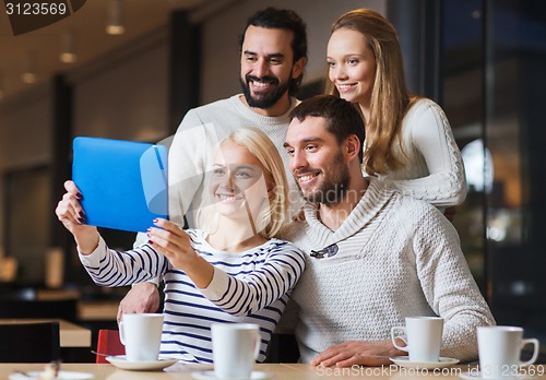 Image of happy friends with tablet pc taking selfie at cafe
