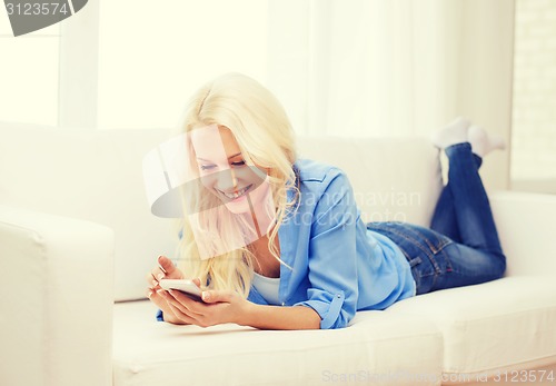 Image of smiling woman with smartphone at home