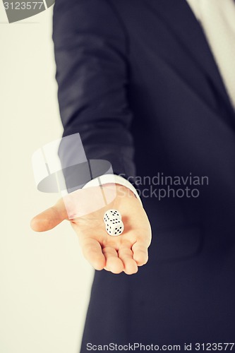 Image of mans hand holding white casino dice
