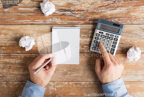 Image of close up of hands with calculator and notebook