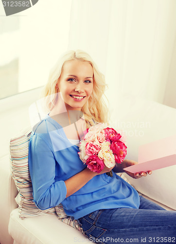 Image of smiling woman with card and bouquet of flowers
