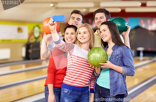 Image of happy friends with smartphone in bowling club