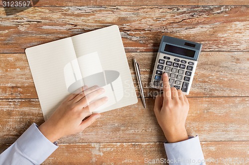 Image of close up of hands with calculator and notebook