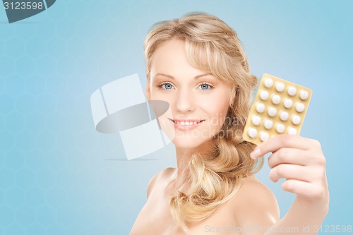 Image of happy young woman holding package of pills