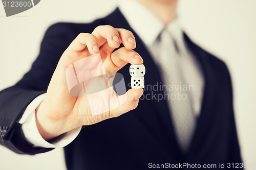 Image of mans hand holding white casino dice