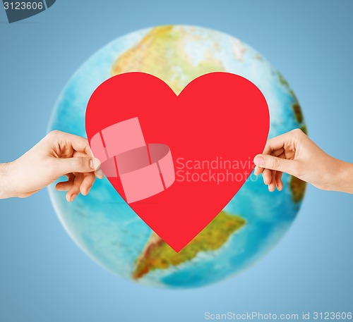 Image of human hands holding red heart over earth globe