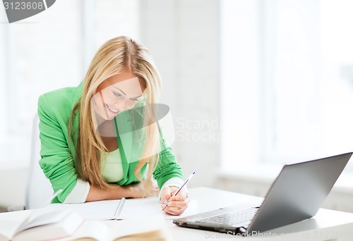 Image of smiling student girl writing in notebook