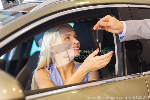 Image of happy woman getting car key in auto show or salon