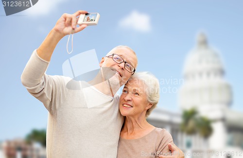 Image of senior couple with camera over white house