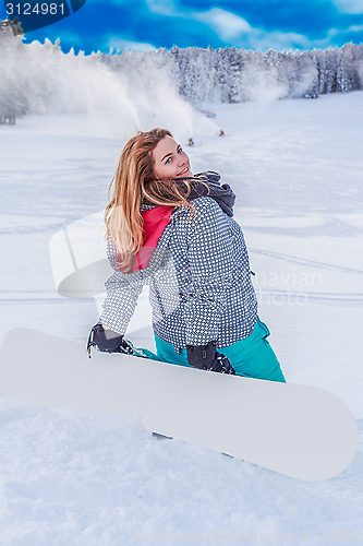 Image of Young chubby woman with a snowboard on the ski slopes, kneeling in the snow